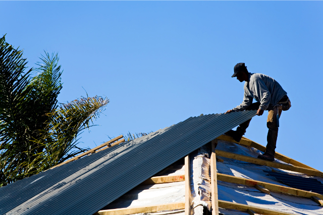 Metal roofer at work installing sheets of metal on the roof.